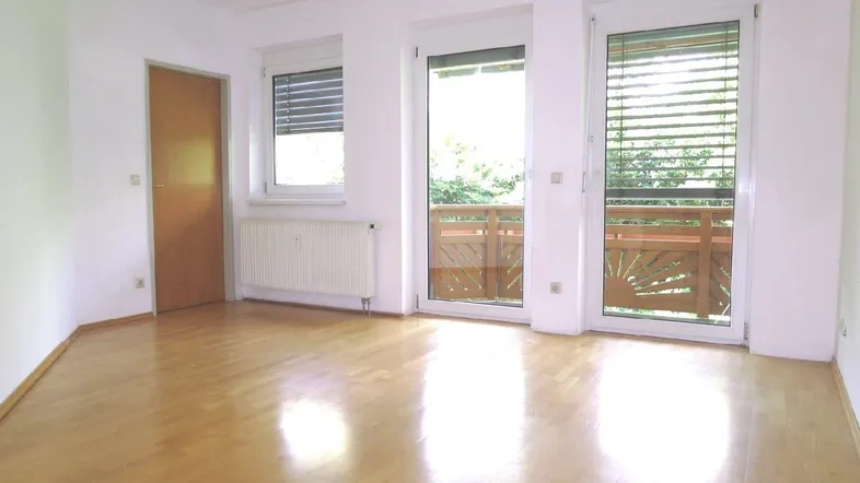 Helles Zimmer mit Parkettboden und Zugang zu zwei Balkonen, ideal als Wohnbereich.