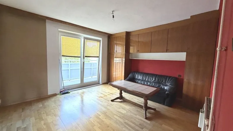 Geräumiges Wohnzimmer mit Parkettboden, Einbauschränken und Zugang zum Balkon.