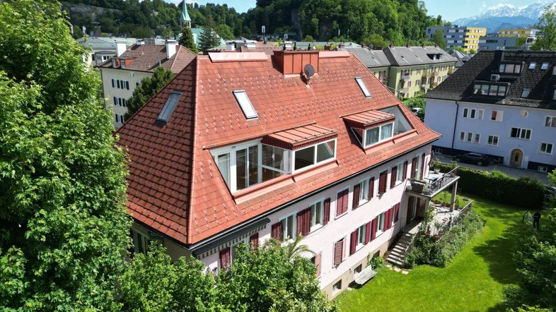 Luftaufnahme eines Mehrfamilienhauses mit rotem Ziegeldach und grüner Umgebung.