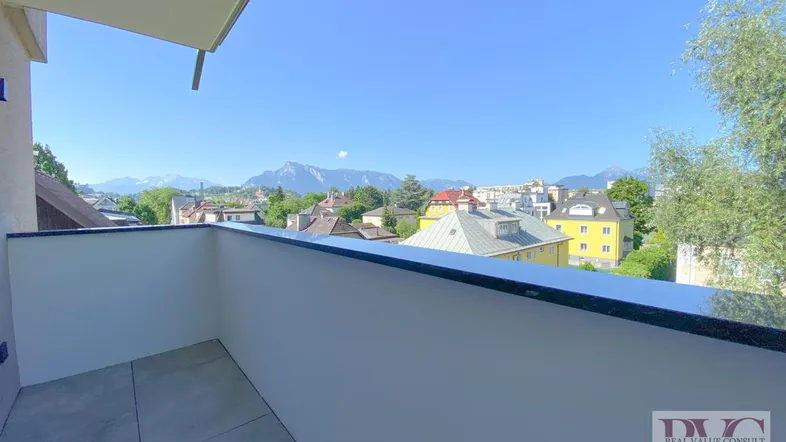 Geräumiger Balkon mit Fliesenboden und weitem Blick auf die Stadt und die umliegenden Berge.