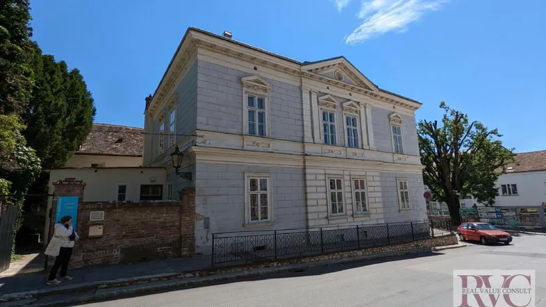 Historisches Gebäude mit klassischer Fassade an einer Straßenecke unter blauem Himmel.