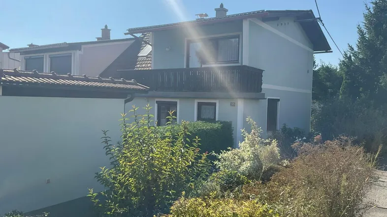 Ansicht des Hauses von der Seite mit Balkon und umgebender Vegetation.