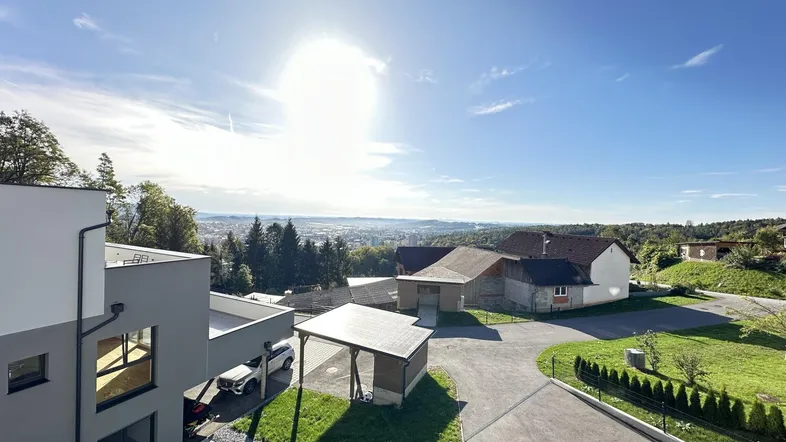 Panoramablick auf die moderne Wohnanlage mit Carport und weitem Horizont unter strahlendem Sonnenschein.
