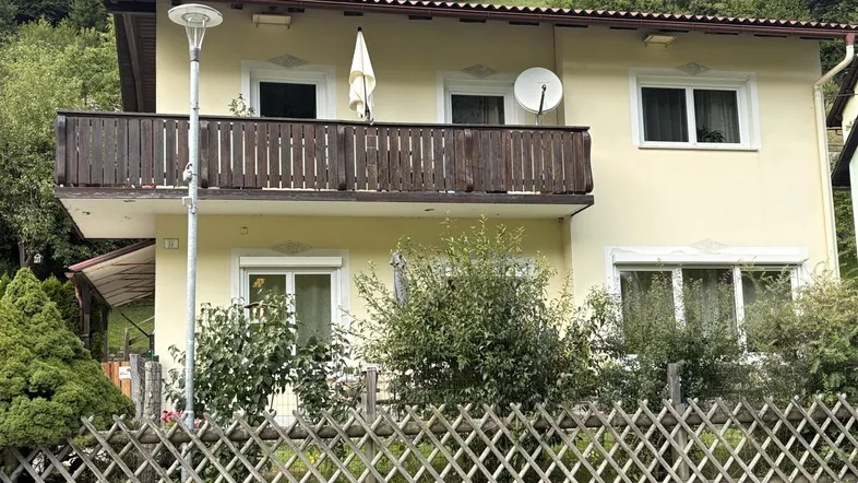 Vorderansicht des Hauses mit Balkon im Obergeschoss und einem kleinen Vorgarten.