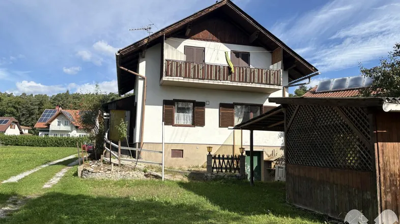 Das Wohnhaus mit Balkon und Satteldach, umgeben von einer grünen Rasenfläche unter blauem Himmel.