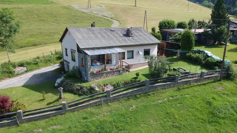 Ländliches Einfamilienhaus mit Garten und überdachtem Eingangsbereich in grüner Umgebung.