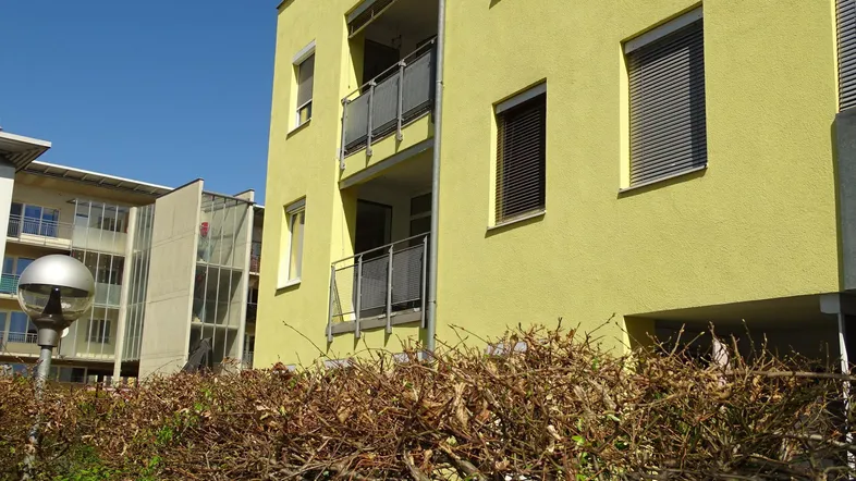 Seitenansicht der modernen Wohnanlage mit gelber Fassade und Balkonen.