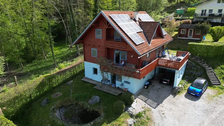 Luftaufnahme des Hauses mit Photovoltaikanlage, Garten und Teich in grüner Umgebung.
