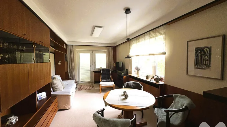 Helles Wohnzimmer mit Essbereich, Holzmöbeln und Zugang zum Balkon.