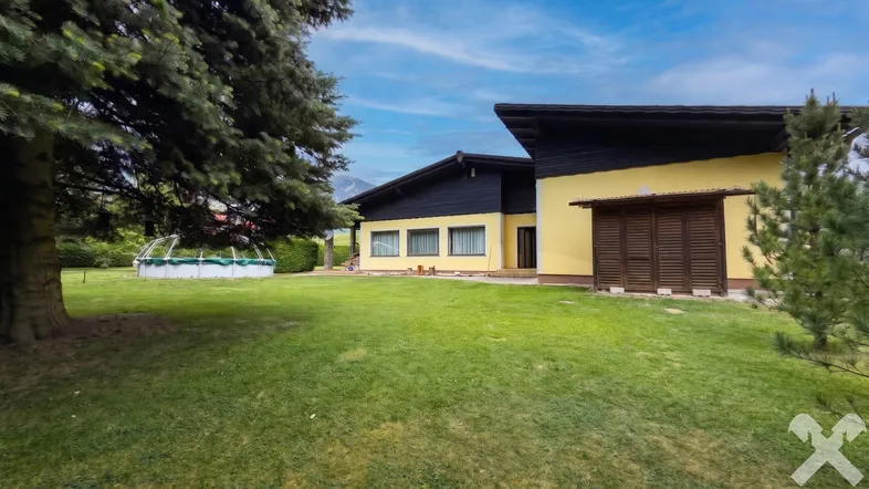 Großer Garten mit Rasenfläche, Nadelbäumen und einem Aufstellpool neben dem Haus.