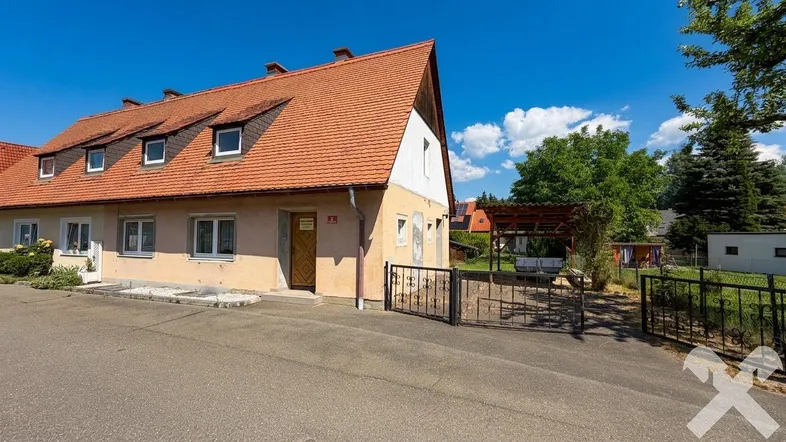 Ansicht des Hauses mit rotem Ziegeldach, Carport und Vorgartenbereich.