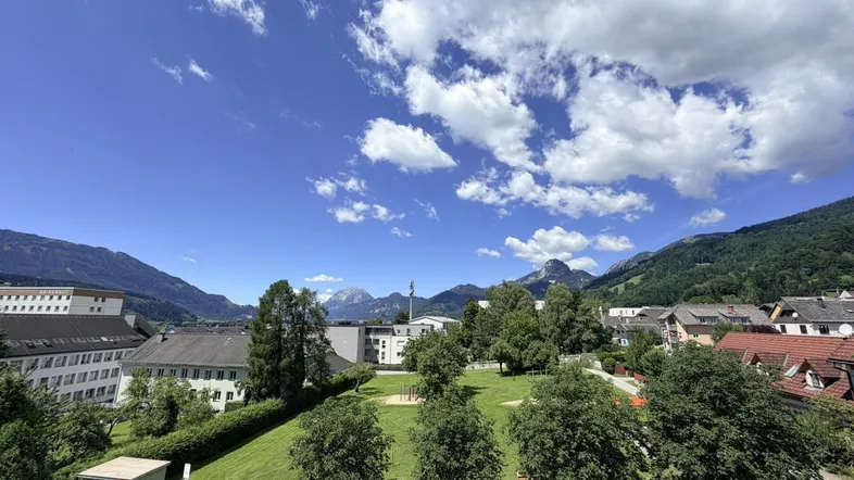 Panoramablick auf grüne Hügel und Berge unter blauem Himmel mit Wolken.