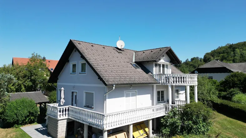 Freistehendes Einfamilienhaus mit mehreren Balkonen und Satteldach in ländlicher Umgebung.