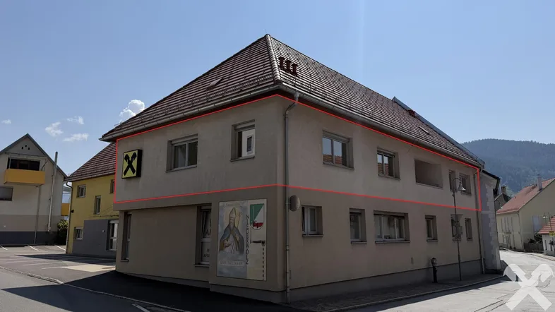 Gebäudeansicht mit traditionellem Satteldach und beiger Fassade in sonniger Umgebung.