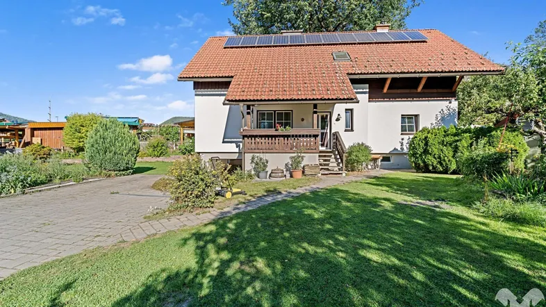 Einfamilienhaus mit Satteldach, Photovoltaikanlage, großem Garten und gepflasterter Auffahrt.