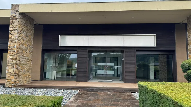 Moderne Geschäftsfassade mit Stein- und Holzverkleidung, großen Glasfronten und gepflegter Außenanlage.