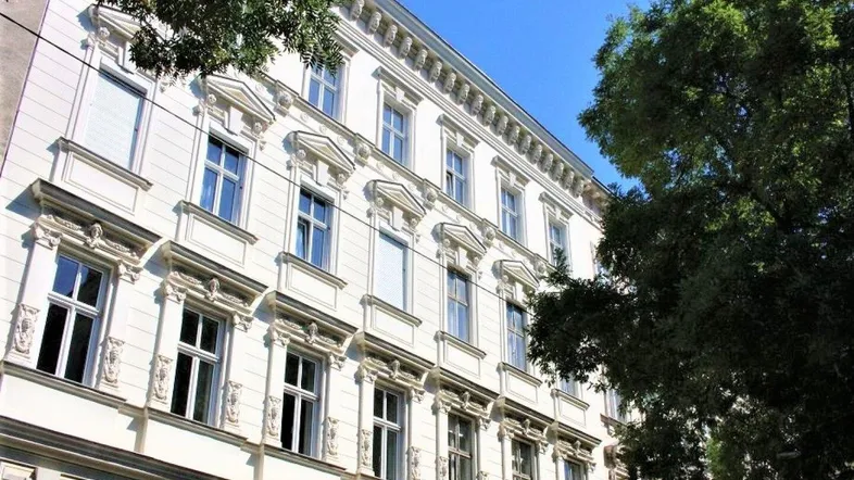 Historisches Gebäude mit reich verzierter Fassade und vielen Fenstern unter blauem Himmel.