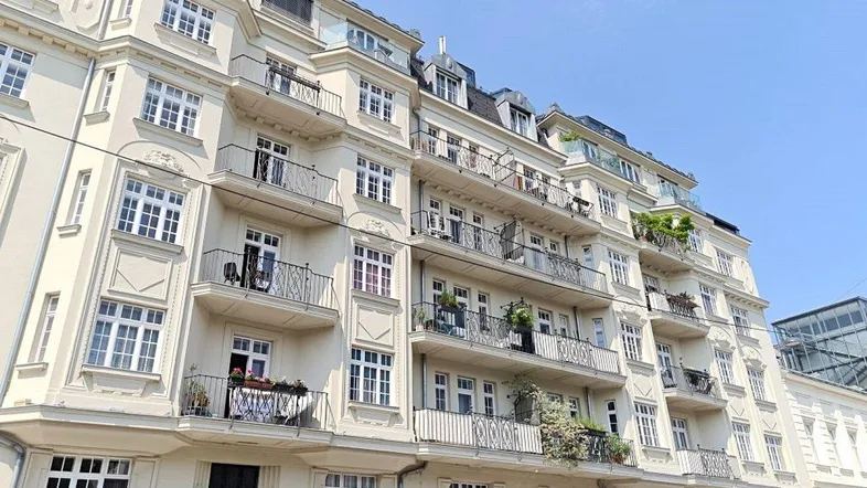 Elegante Fassade eines Mehrfamilienhauses mit zahlreichen Balkonen unter blauem Himmel.