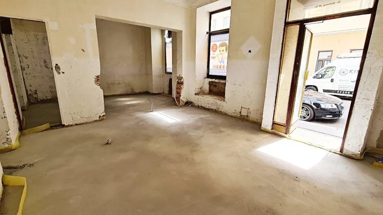 Innenraum im Rohbauzustand mit Betonboden und freigelegten Wänden, bereit für den Ausbau.
