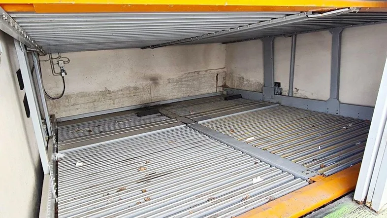 Innenansicht einer Tiefgarage mit mechanischem Parksystem für zwei Fahrzeuge und Betonwänden.