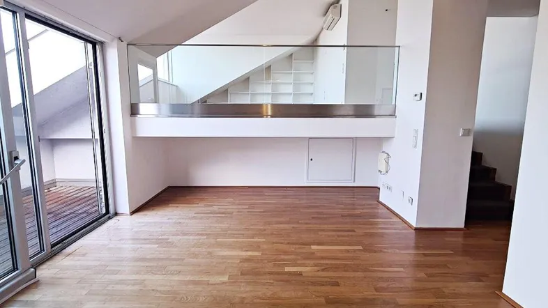 Geräumiger Wohnbereich mit Holzboden, großen Schiebetüren zur Terrasse und einer Galerieebene.