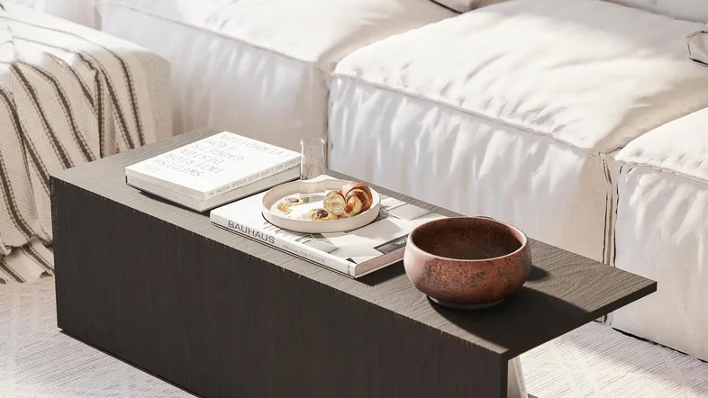 Moderner Couchtisch mit Dekoration vor einem bequemen weißen Sofa in einem hellen Wohnzimmer.
