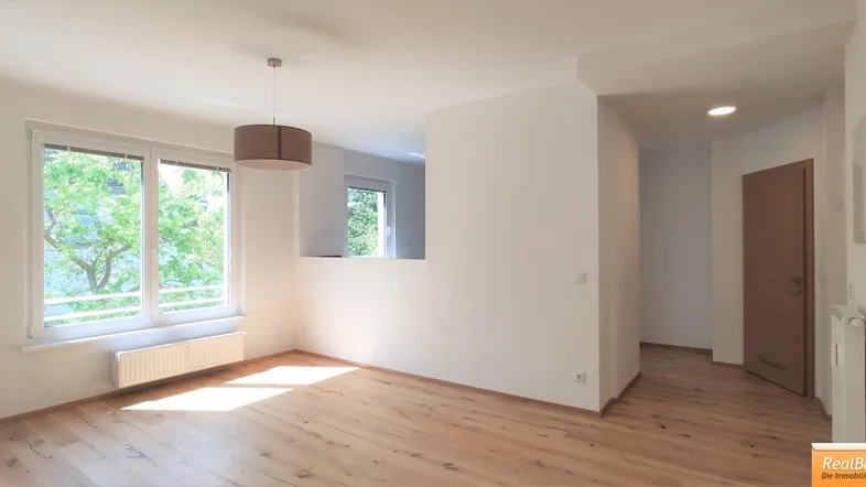 Helles Wohnzimmer mit Holzboden, großen Fenstern und Blick ins Grüne.