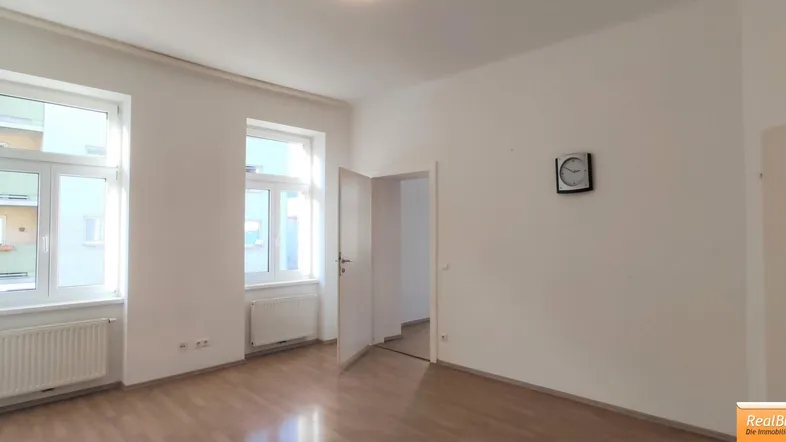 Helles Zimmer mit Holzboden und zwei Fenstern, ideal als Wohn- oder Schlafzimmer nutzbar.