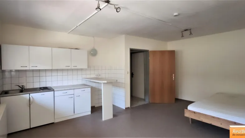 Helles Studio-Apartment mit integrierter Küchenzeile und Schlafbereich, ideal für Singles.