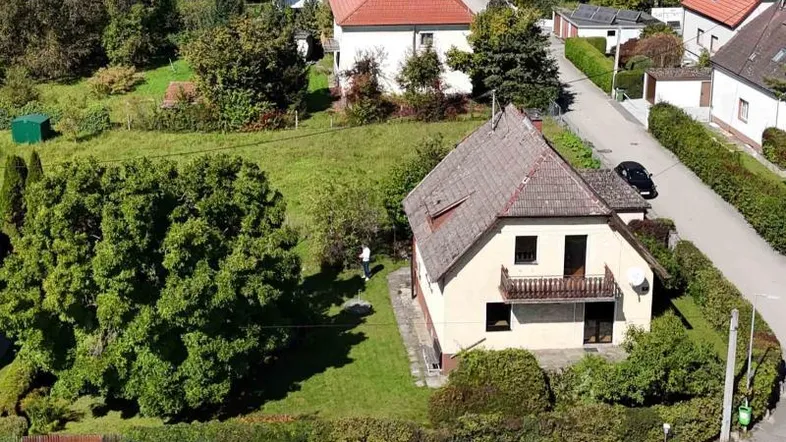 Luftaufnahme eines Einfamilienhauses mit großem Garten und umliegender Wohnsiedlung.
