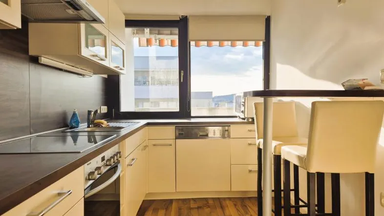 Helle Küche mit Einbauküche, Frühstücksbar und Blick nach draußen durch das Fenster.