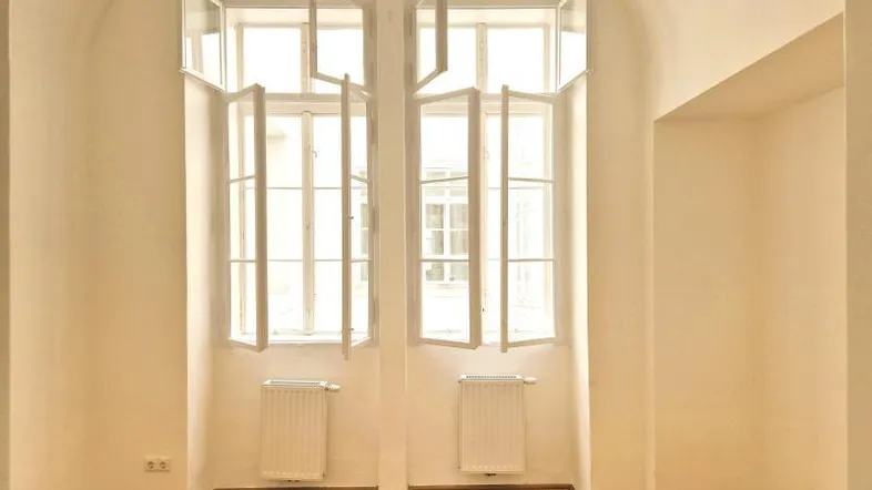 Heller Raum mit hohen Fenstern, Fischgrätparkett und gewölbter Decke, ideal für Wohn- oder Schlafbereich.