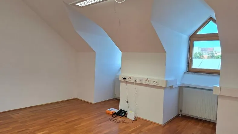 Heller Dachraum mit Holzfußboden, schrägen Wänden und einem Fenster, bereit zur Nutzung.