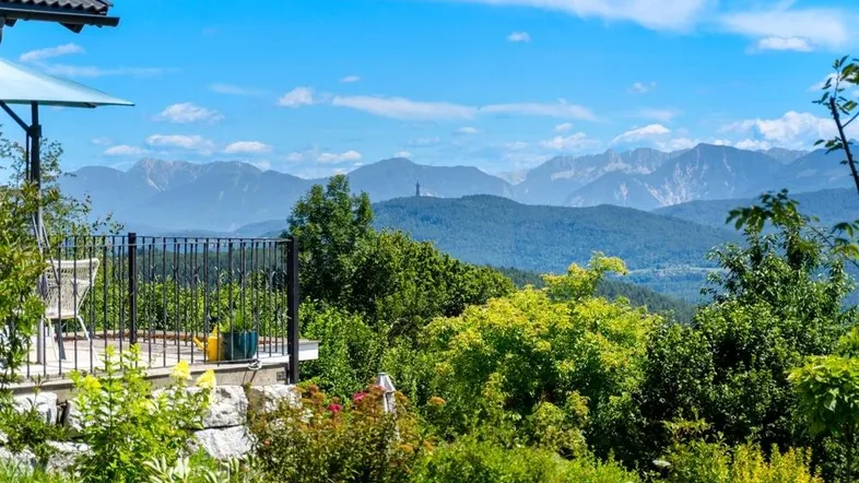 Terrasse mit atemberaubendem Bergblick und üppiger grüner Landschaft unter blauem Himmel.
