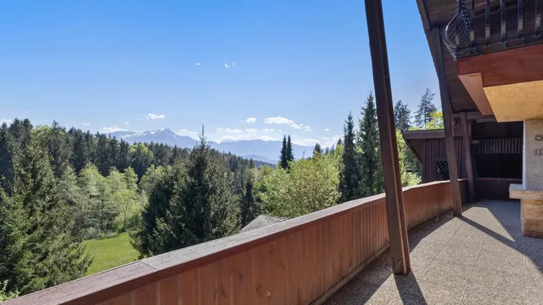 Geräumiger Balkon mit Holzbalken und weitem Blick auf die umliegende Berglandschaft und Wälder.