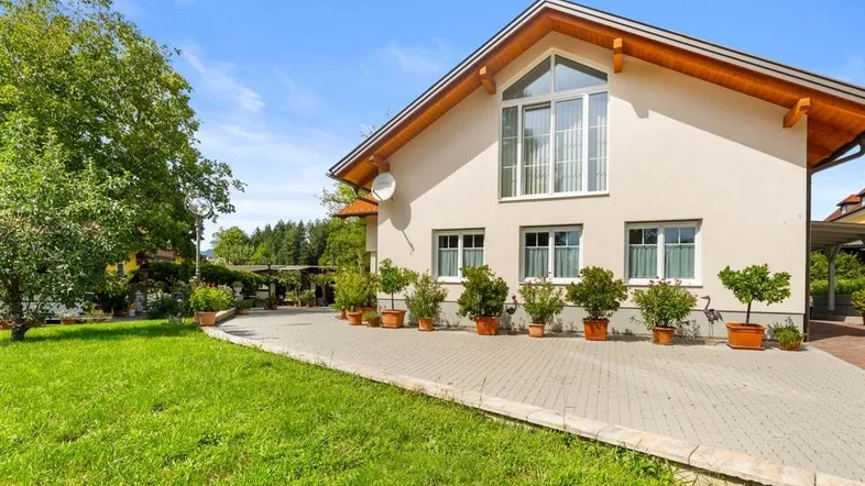 Modernes Einfamilienhaus mit gepflegtem Vorgarten und breiter Auffahrt unter blauem Himmel.