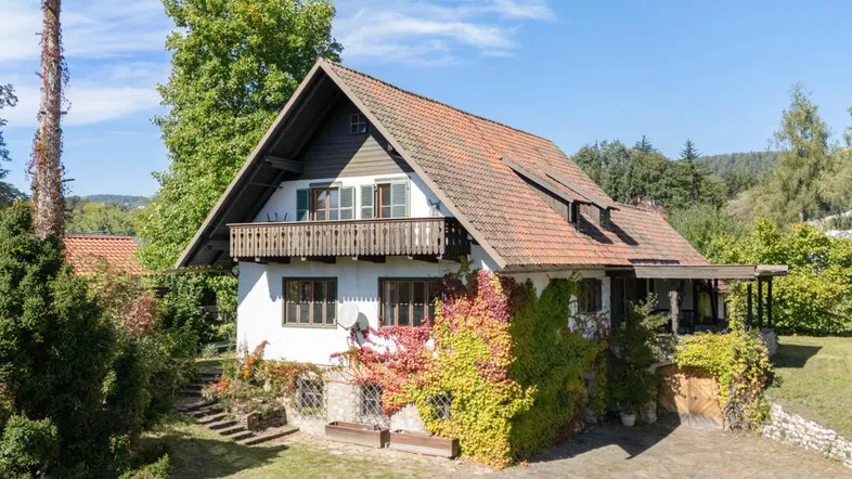 Charmantes Haus mit bewachsener Fassade, Holzbalkon und traditionellem Satteldach.