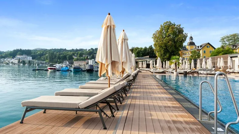 Exklusiver Poolbereich mit Holzdeck, Liegestühlen und direktem Zugang zum Seeufer.