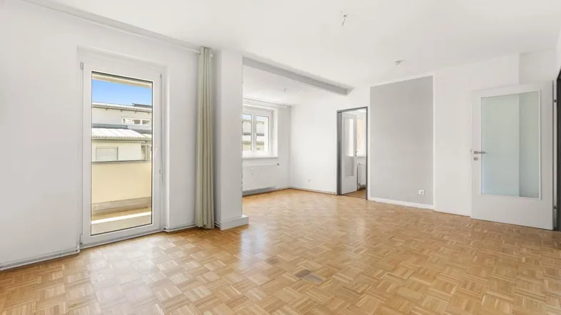 Helles Wohnzimmer mit Parkettboden und Zugang zu einem Balkon, bereit zur individuellen Gestaltung.