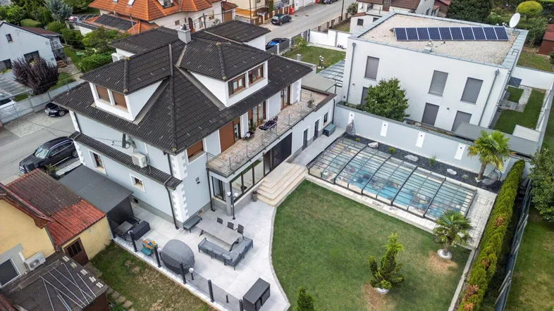 Luftaufnahme des Anwesens mit großem Garten, Pool und Terrasse, umgeben von Wohnbebauung.