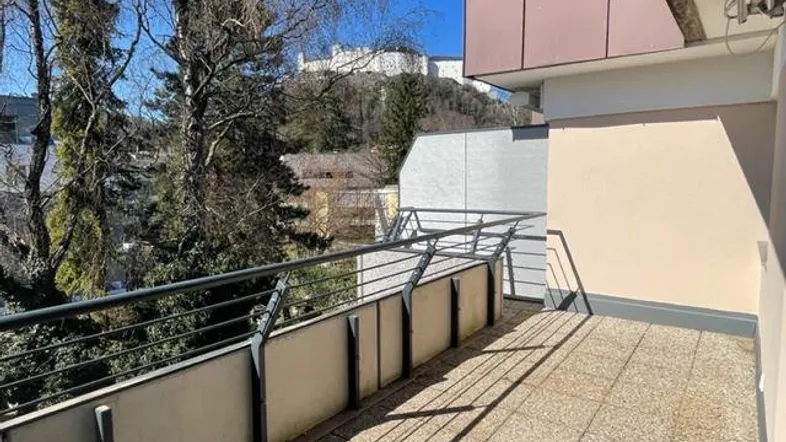 Geräumiger Balkon mit Fliesenboden und Panoramablick auf die Festung Hohensalzburg und grüne Umgebung.