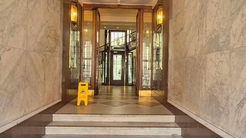 Elegante Eingangshalle mit Marmorwänden, hohen Decken und einer breiten Treppe.