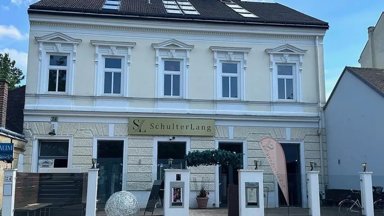 Klassische Fassade eines Mehrfamilienhauses mit dekorativen Fenstern und einem Restaurant im Erdgeschoss.