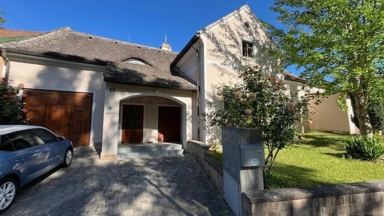 Vorderansicht des Hauses mit gepflasterter Einfahrt, Garage und einem gepflegten Vorgarten.