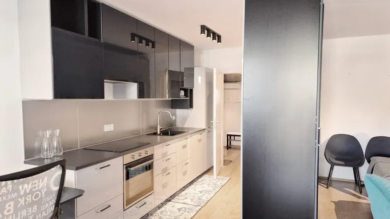 Moderne Küchenzeile mit grauen Hochglanzfronten, integriertem Backofen und Kochfeld.