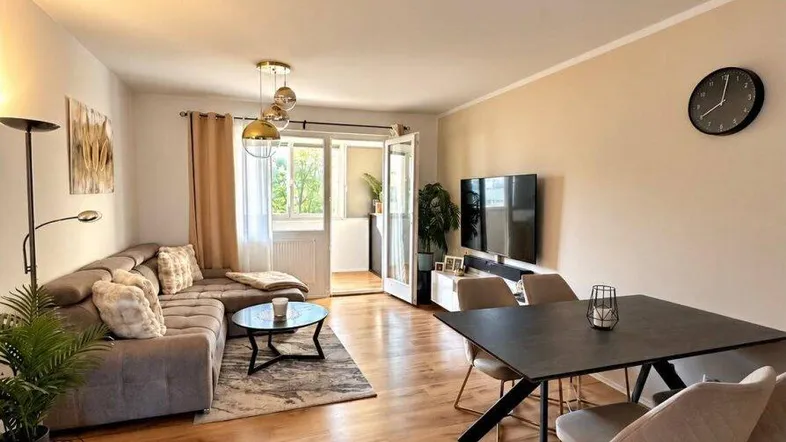 Heller Wohn-Essbereich mit modernem Sofa, Esstisch und Zugang zu einem Balkon.