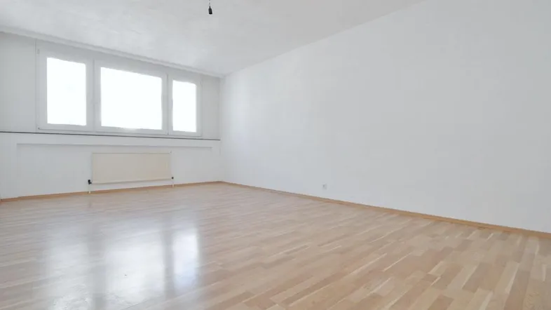 Helles, leeres Zimmer mit Parkettboden und großen Fenstern, bereit zur individuellen Gestaltung.
