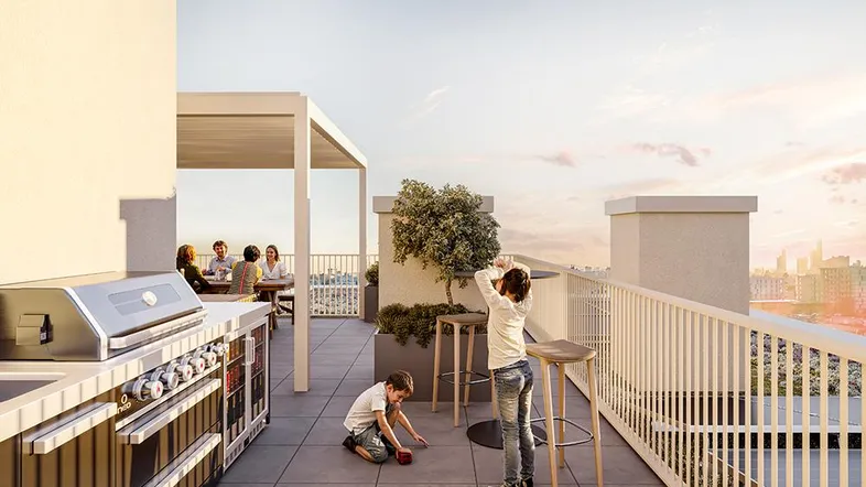 Geräumige Dachterrasse mit moderner Außenküche, Essbereich und Blick auf die Stadt bei Sonnenuntergang.