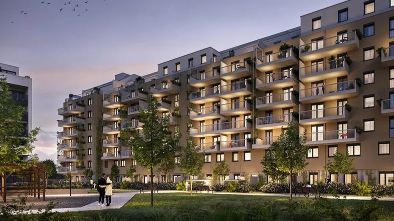 Moderne Wohnanlage mit zahlreichen Balkonen und einem begrünten Innenhof bei Dämmerung.
