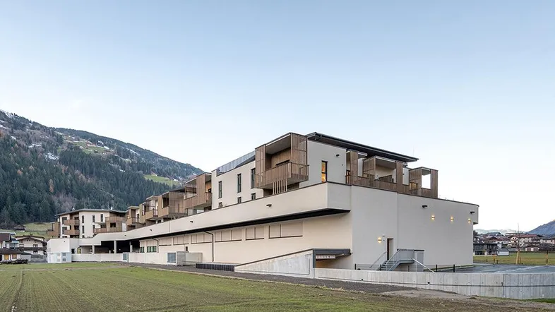 Modernes Mehrfamilienhaus mit Balkonen, Photovoltaikanlage und Bergblick in ländlicher Umgebung.